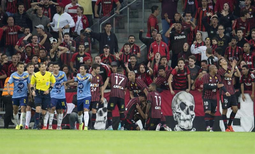 Jugadores (d) de Atlético Paranaense de Brasil celebran un gol mientras jugadores de Sportivo Luqueño de Paraguay le reclaman al árbitro Víctor Carrillo (3-i) hoy, miércoles 21 de octubre de 2015, durante un partido de los cuartos de final de la Copa Sudamericana en el estadio Arena da Baixada en Curitiba (Brasil). EFE/Hedeson Alves
