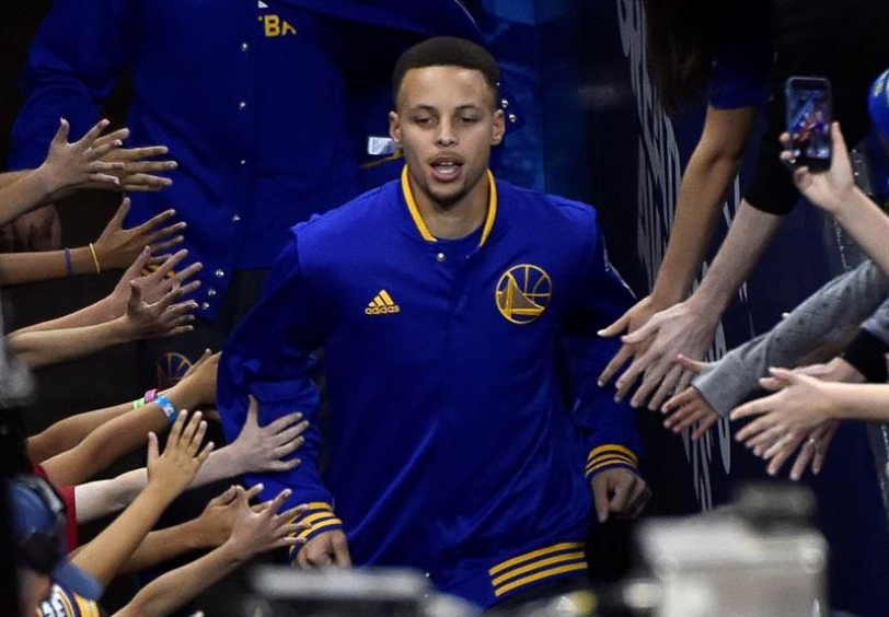 El jugador de los Golden State Warriors Stephen Curry saluda a los aficionados a su llegada al campo antes del comienzo del partido de la NBA